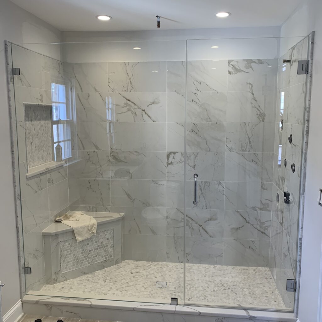 Inline shower with marble and seat in corner installed by Harmony Glass